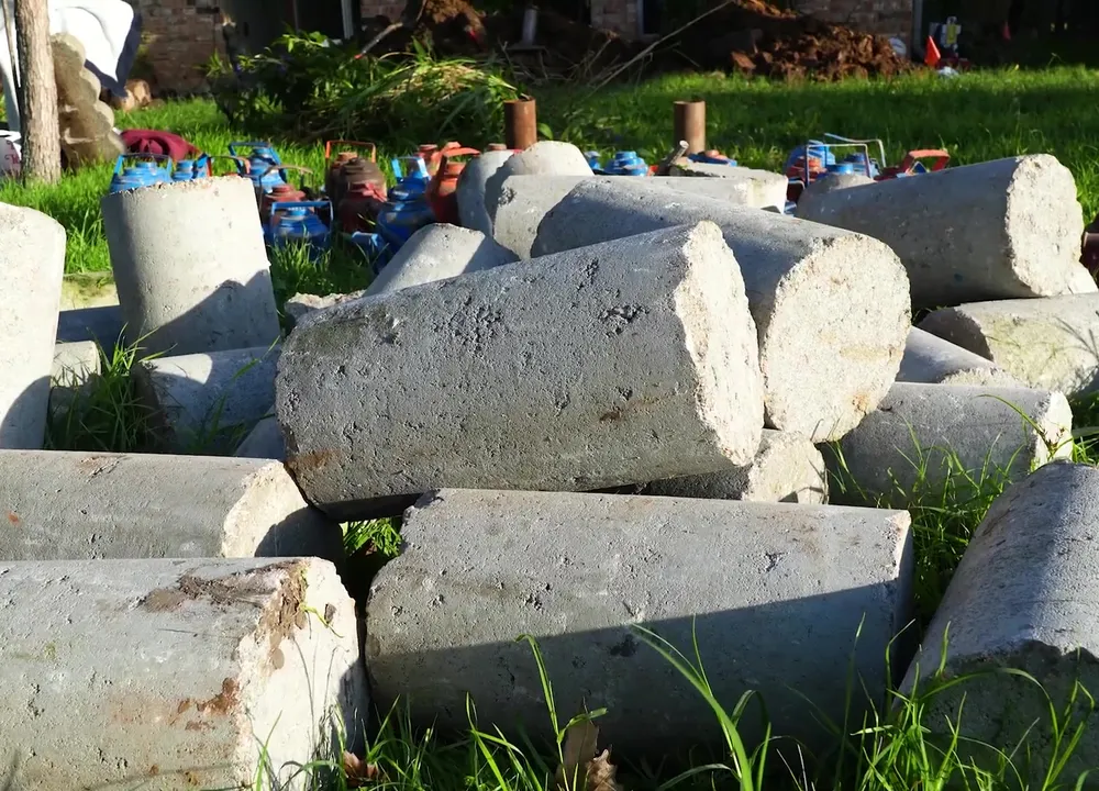 Concrete underpinning pilings staged beside a Pflugerville slab foundation